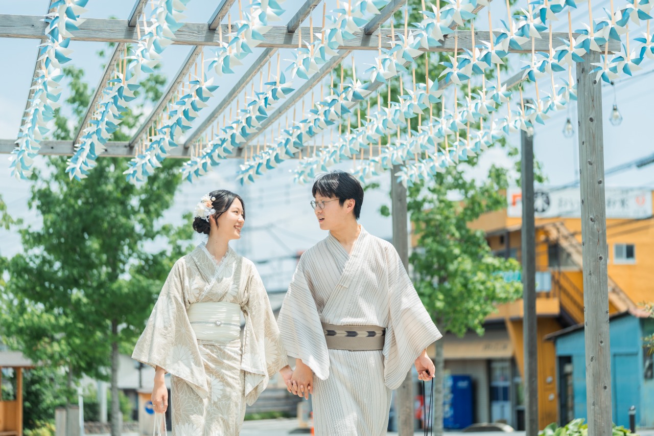 Kawagoe photoshoot couple walking beneath blue hanging decorations in a sunlit courtyard