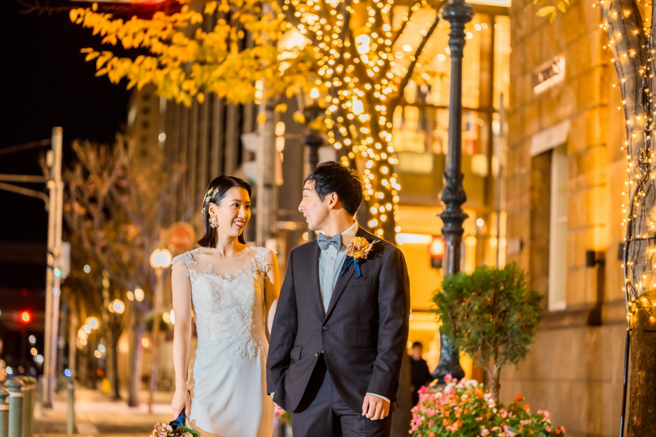 Couple walking on a tree-lit street at night