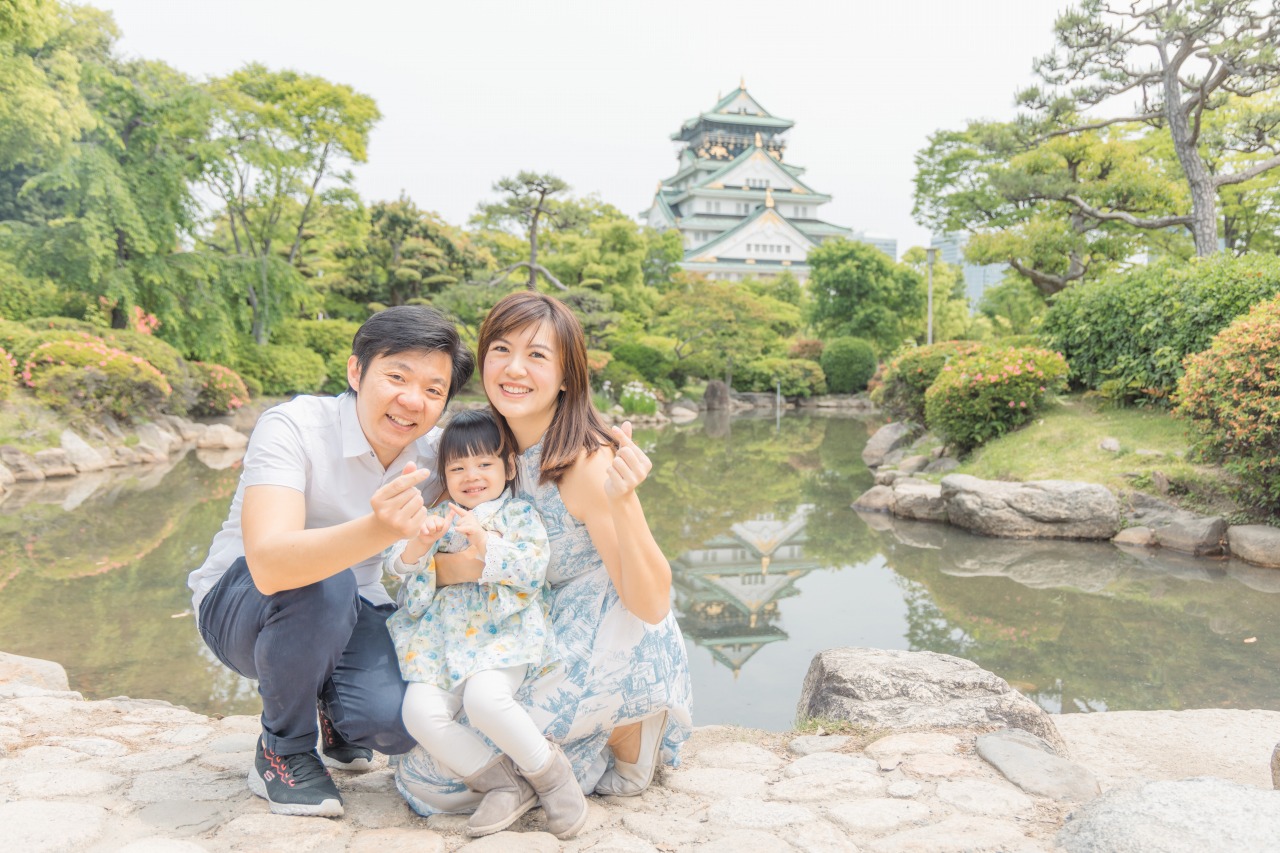 Osaka Castle Park family by pond – walking together, castle in background