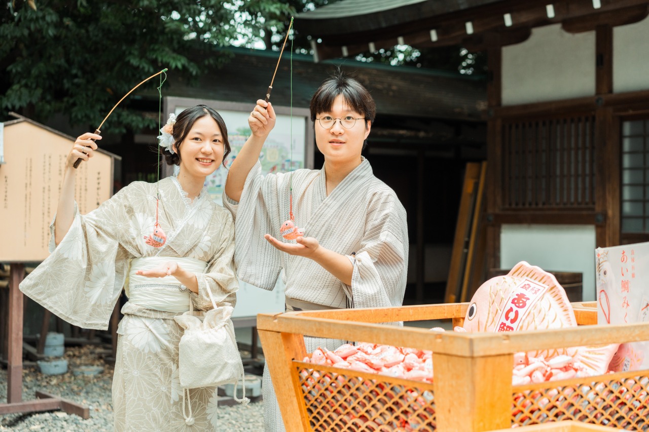 Kawagoe shrine candid – couple holding shrine charms beside offertory area