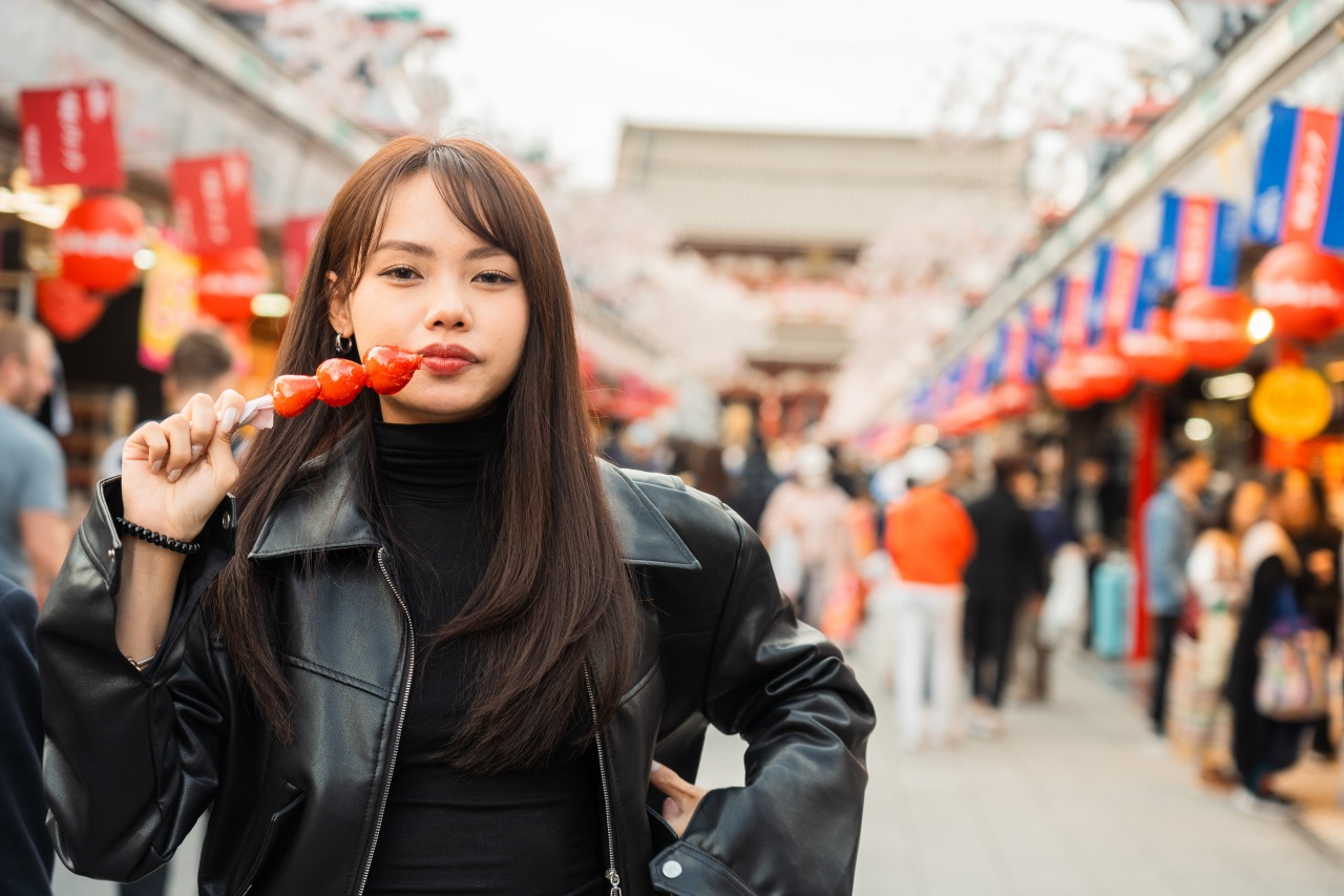 Nakamise shopping street food - woman with snack, festival stalls bokeh