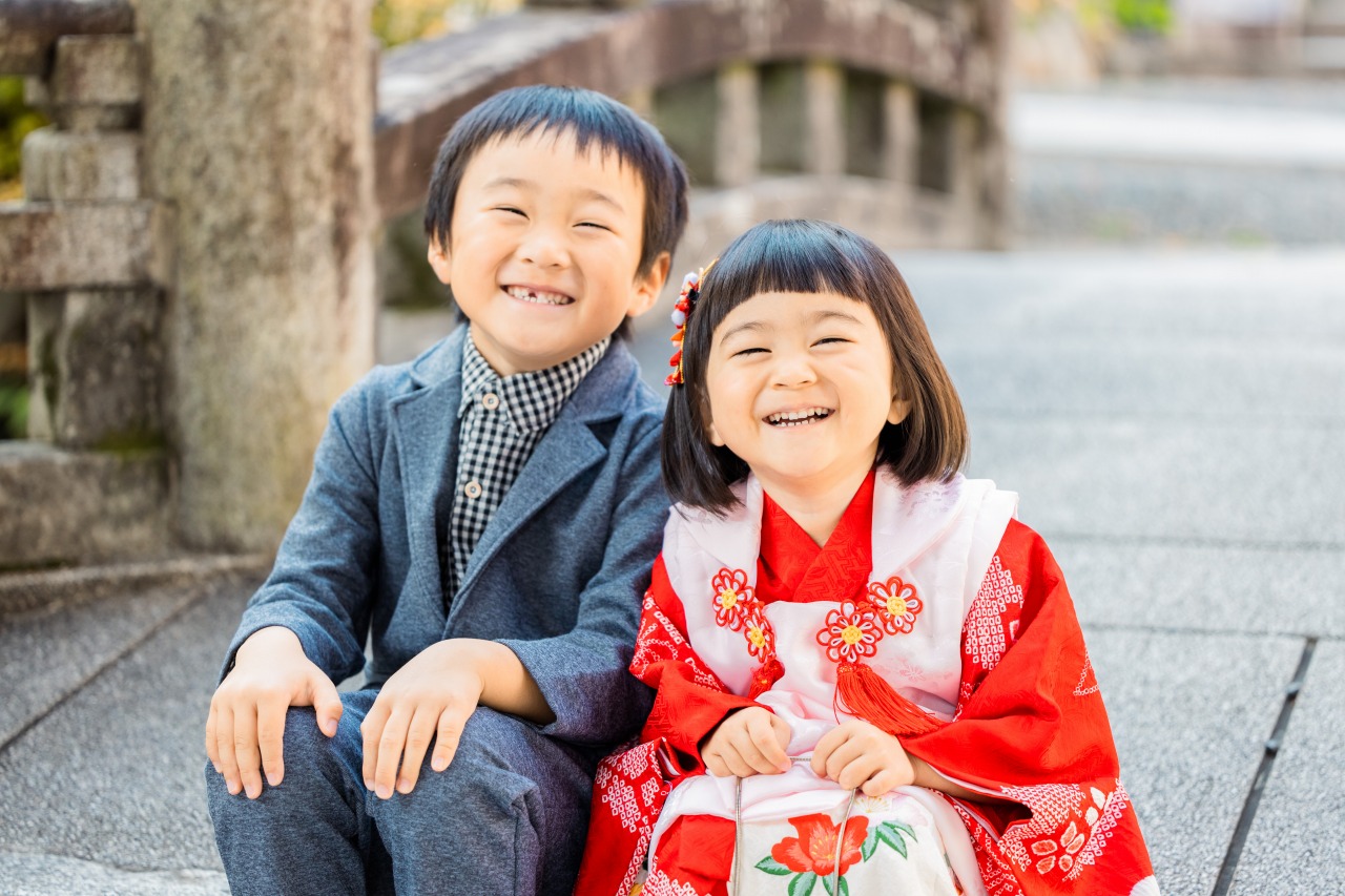 七五三のきょうだいが屋外のベンチで笑顔(和装とスーツ)