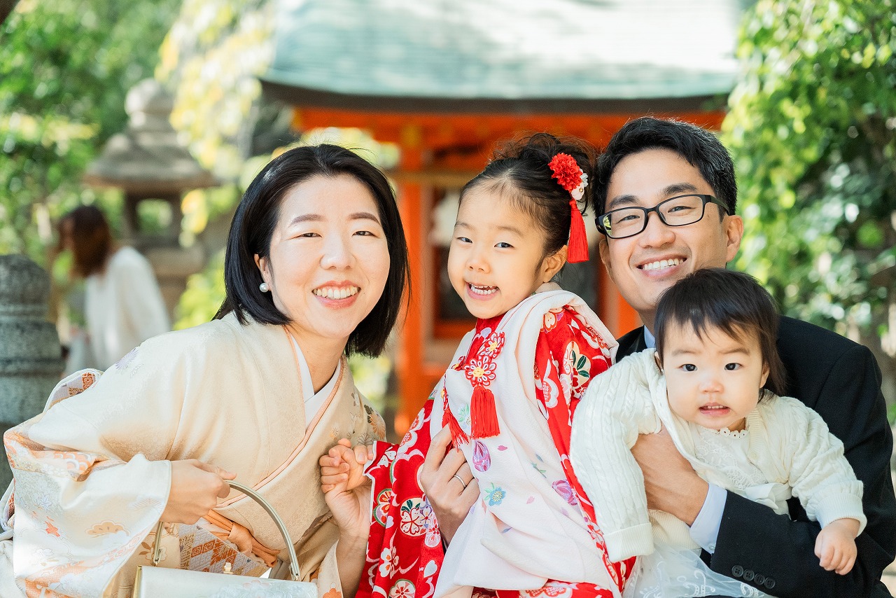 生田神社 七五三 家族写真 赤い着物の女の子と両親が笑顔で並ぶ記念ショット