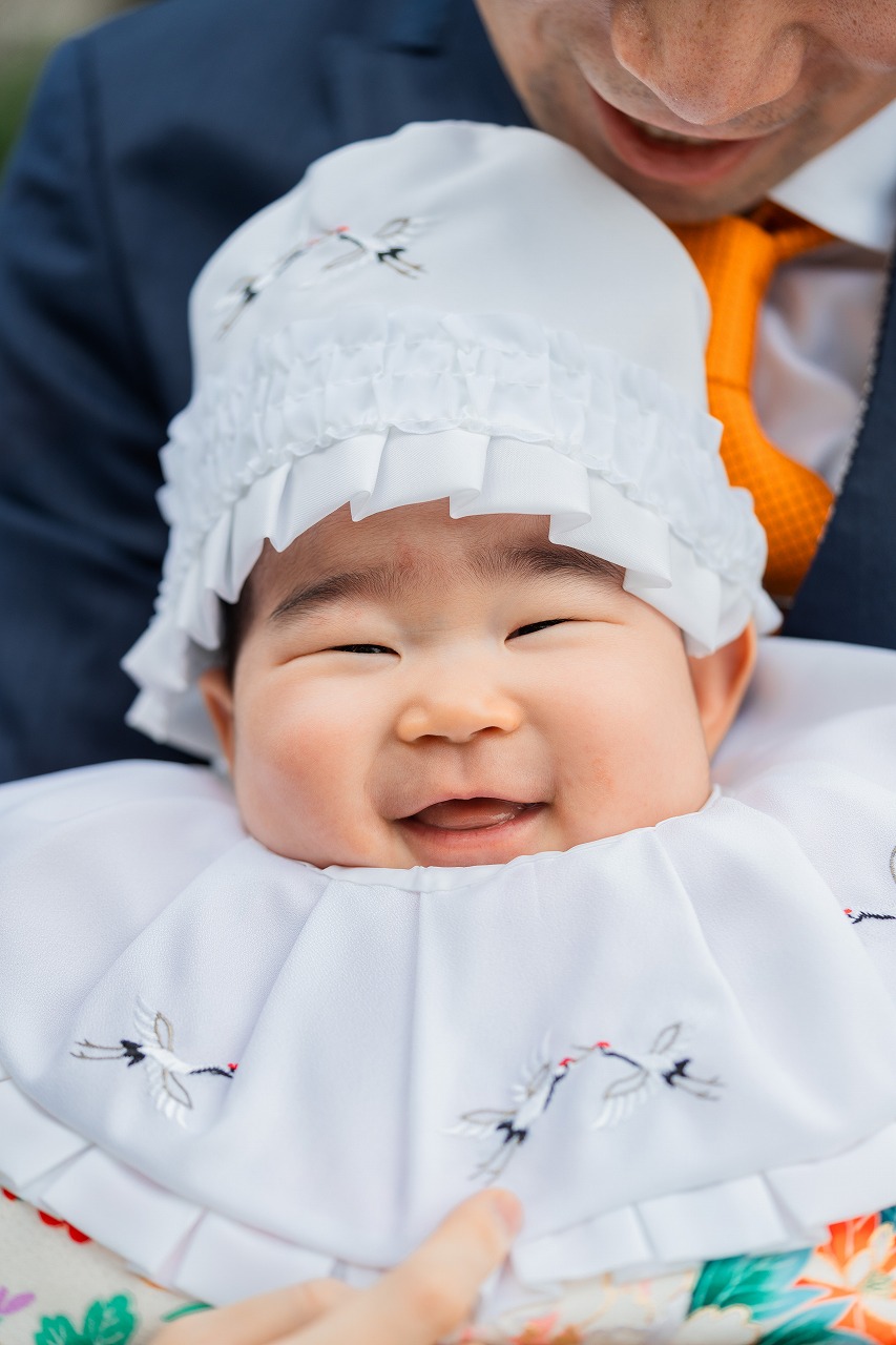 目黒不動尊 お宮参り 赤ちゃんの笑顔アップ 祝い着と帽子が見える寄りカット
