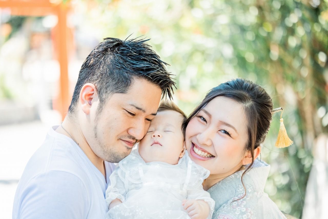 綱敷天満宮 お宮参り パパママに頬寄せる赤ちゃんのアップ やわらかな逆光ポートレート