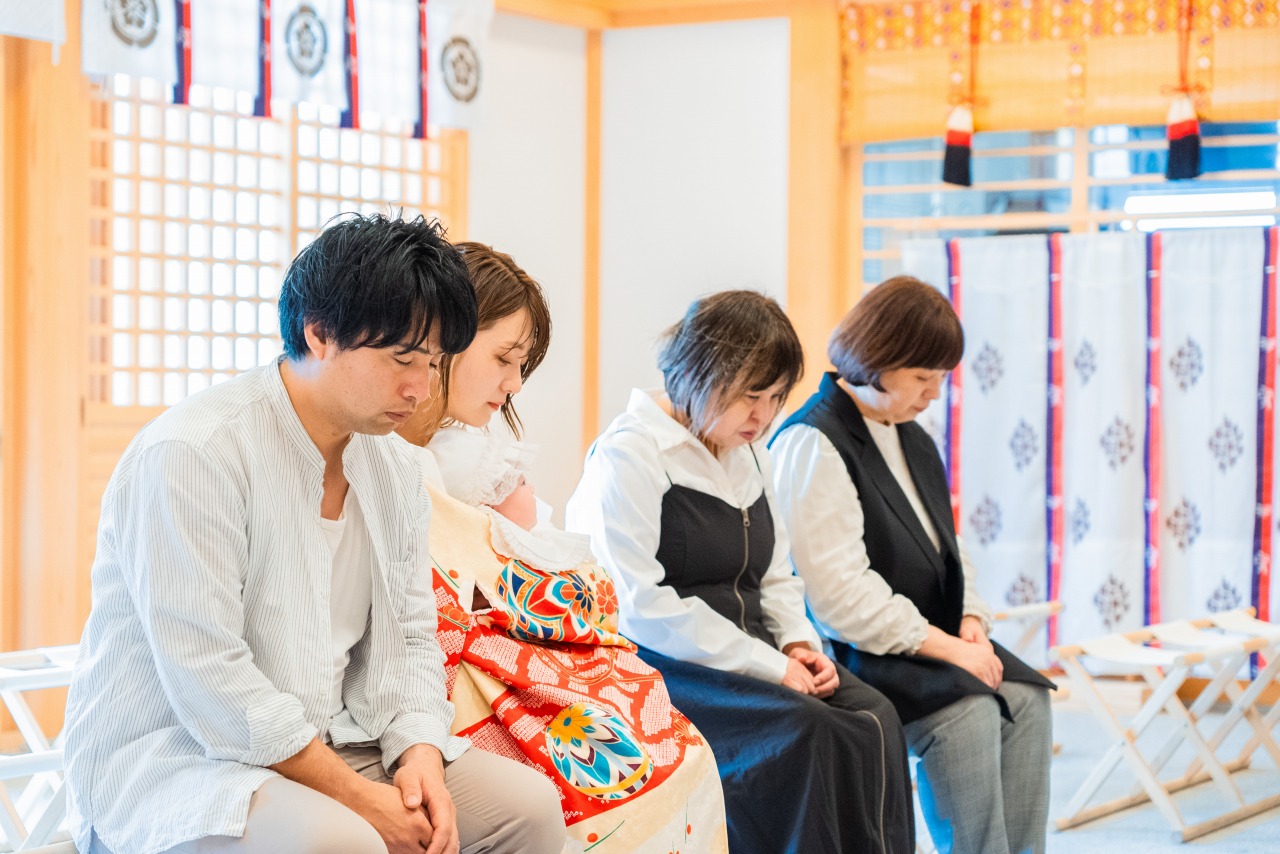 茨木神社 お宮参り ご祈祷中の家族写真 拝殿内で椅子に座る親族の記念カット