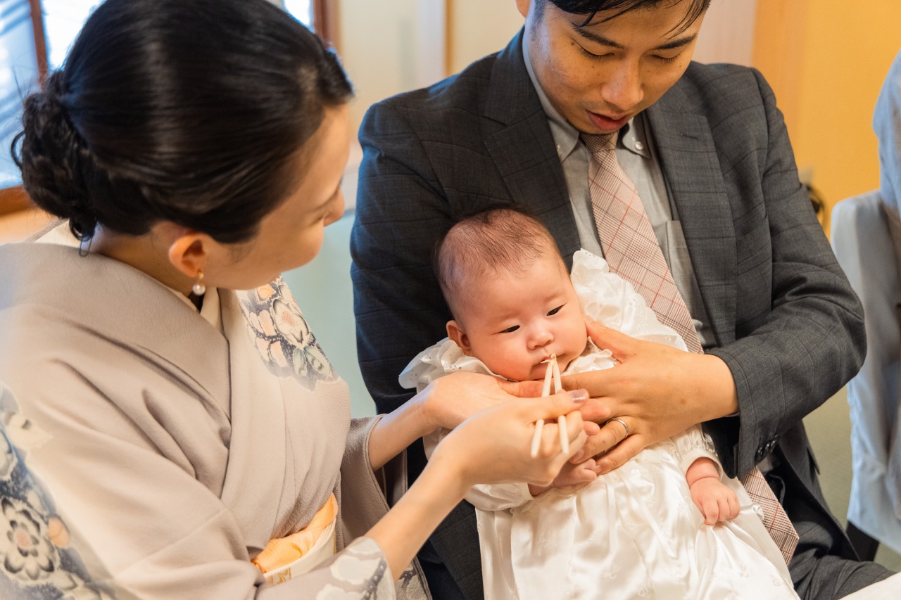 神戸 お食い初め パパが赤ちゃんを抱いて口元へ箸を運ぶカット