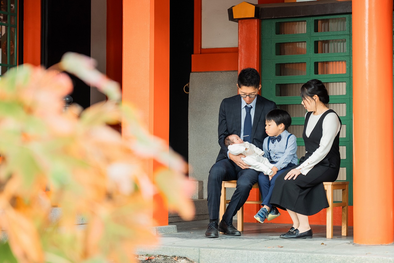 豊中稲荷神社 お宮参り 家族スナップ 回廊の柱前 腰掛けて団らんする雰囲気