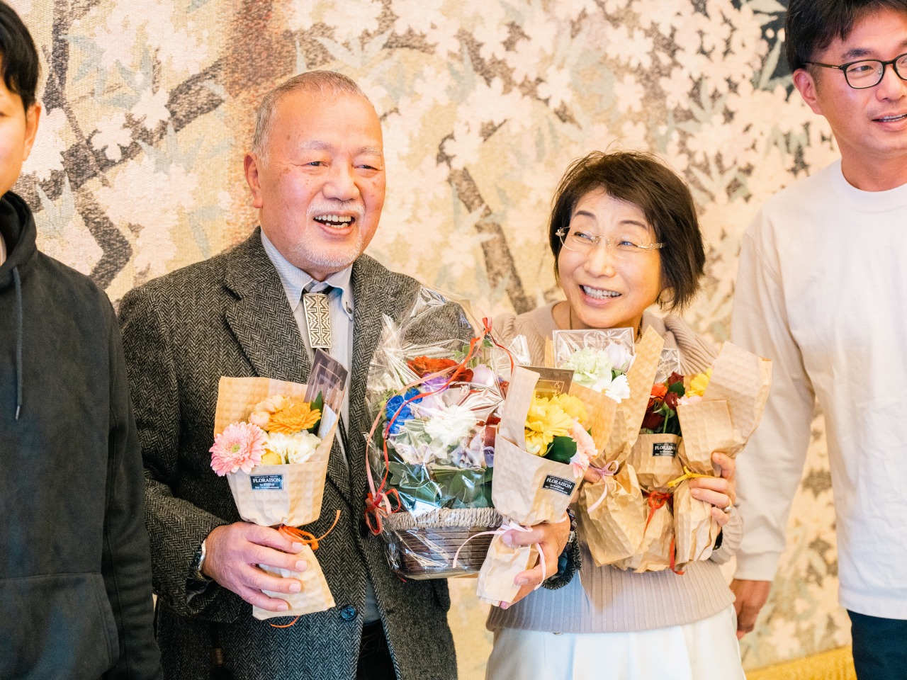 還暦祝い 家族写真 花束を持つご夫婦と家族の笑顔